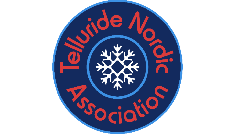 The image is a circular logo with a dark blue background and a light blue border. Inside, there's a white snowflake in the center, symbolizing our work in winter sports. Around the edge, it reads "Telluride Nordic Association" in red text, reflecting our commitment to the community.